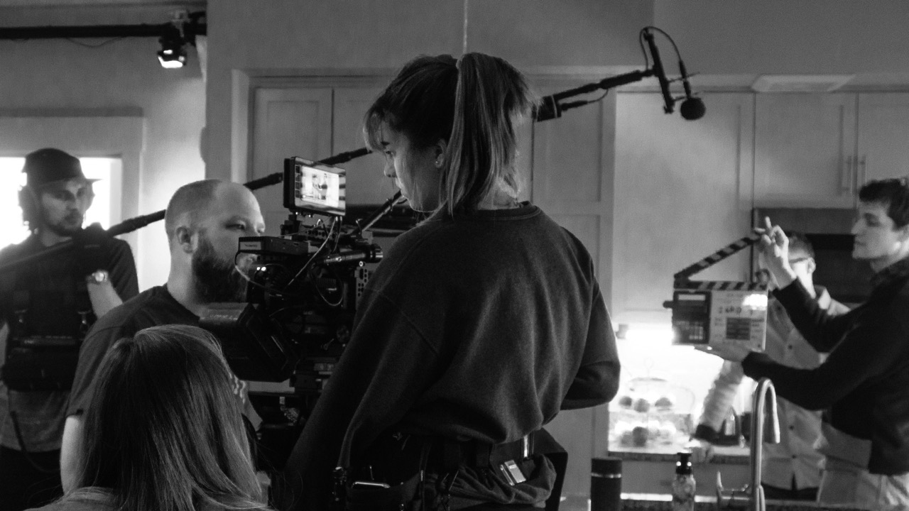 A film crew at work around a camera on a kitchen set
